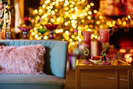Pink and green glass-blown drinkware displayed on a table in a holiday party setting.